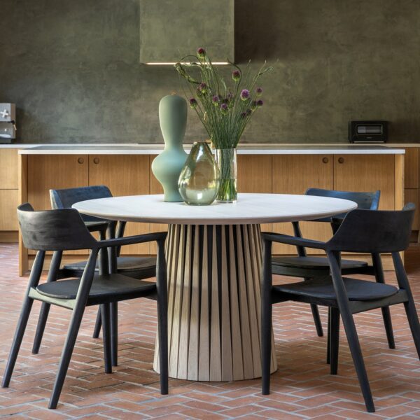 Modern black teak dining chair with arms, shown around round dining table