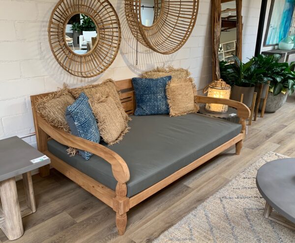 Outdoor teak daybed with cushion in patio setting