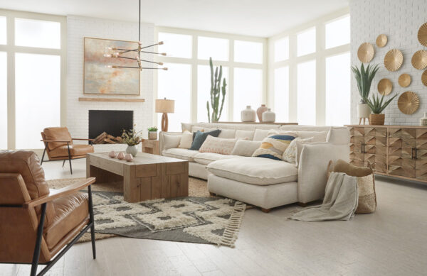 Bright living room setting with white sectional, brown leather club chairs, light brown wood coffee table and sideboard.